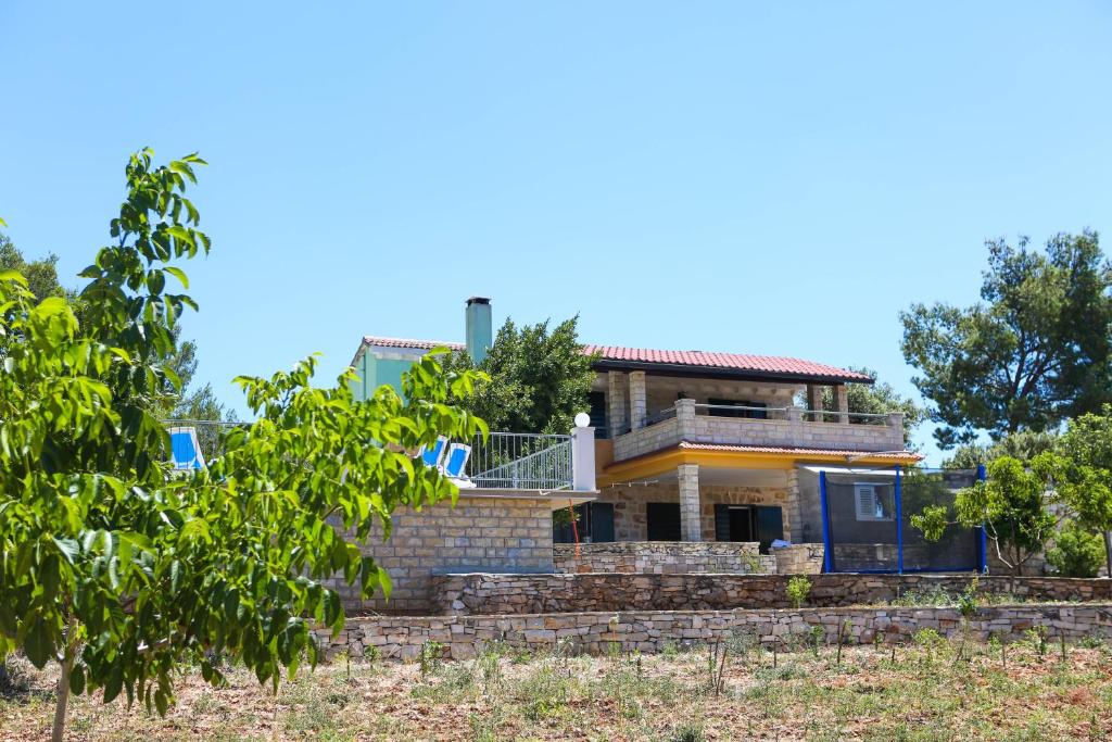 ein Haus auf einem Hügel mit Bäumen im Vordergrund in der Unterkunft Family friendly house with a swimming pool Zavalatica, Korcula - 9476 in Zavalatica