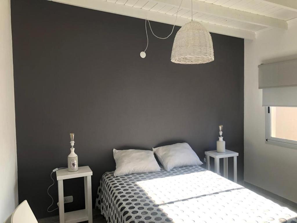 1 dormitorio con cama y pared negra en La Lucia en San Clemente del Tuyú