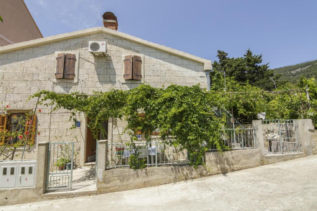 una vieja casa de piedra con una valla delante de ella en Apartments by the sea Komiza, Vis - 11671, en Komiža