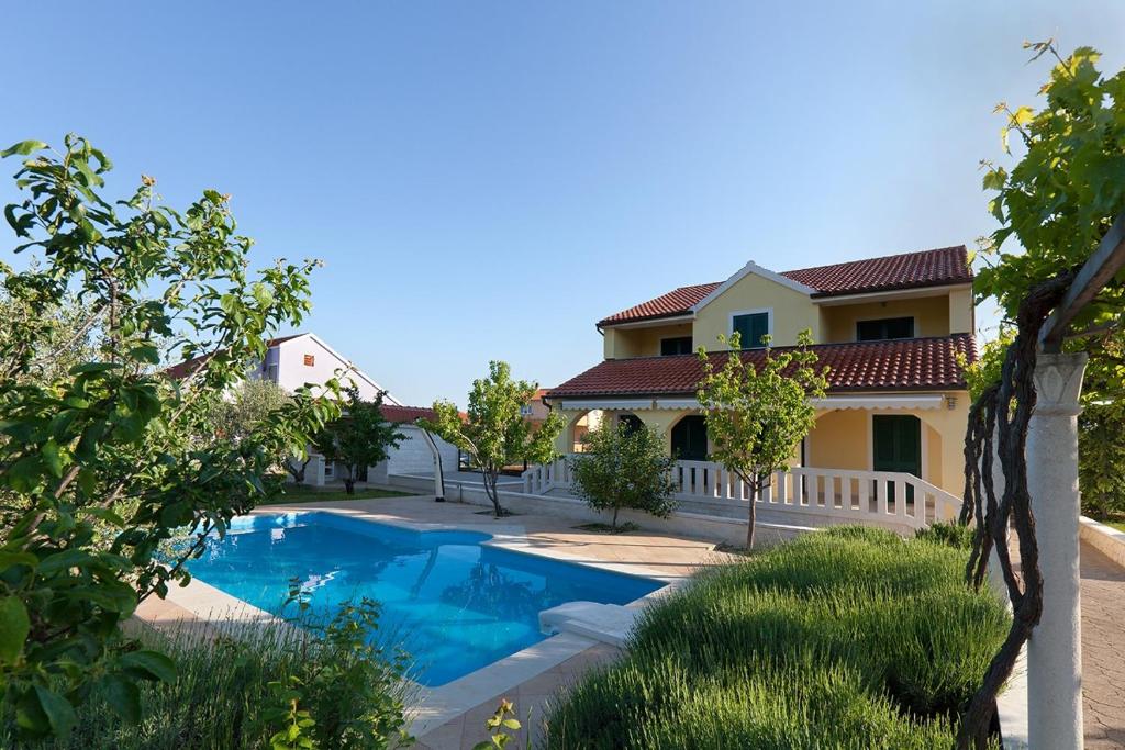 a villa with a swimming pool in front of a house at Holiday house with a swimming pool Lozovac, Krka - 11715 in Lozovac