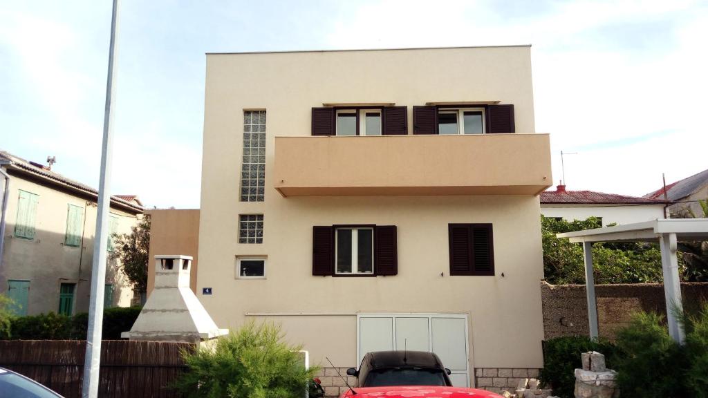 a white house with black shutters on it at Apartments by the sea Vranjic, Split - 11753 in Vranjic