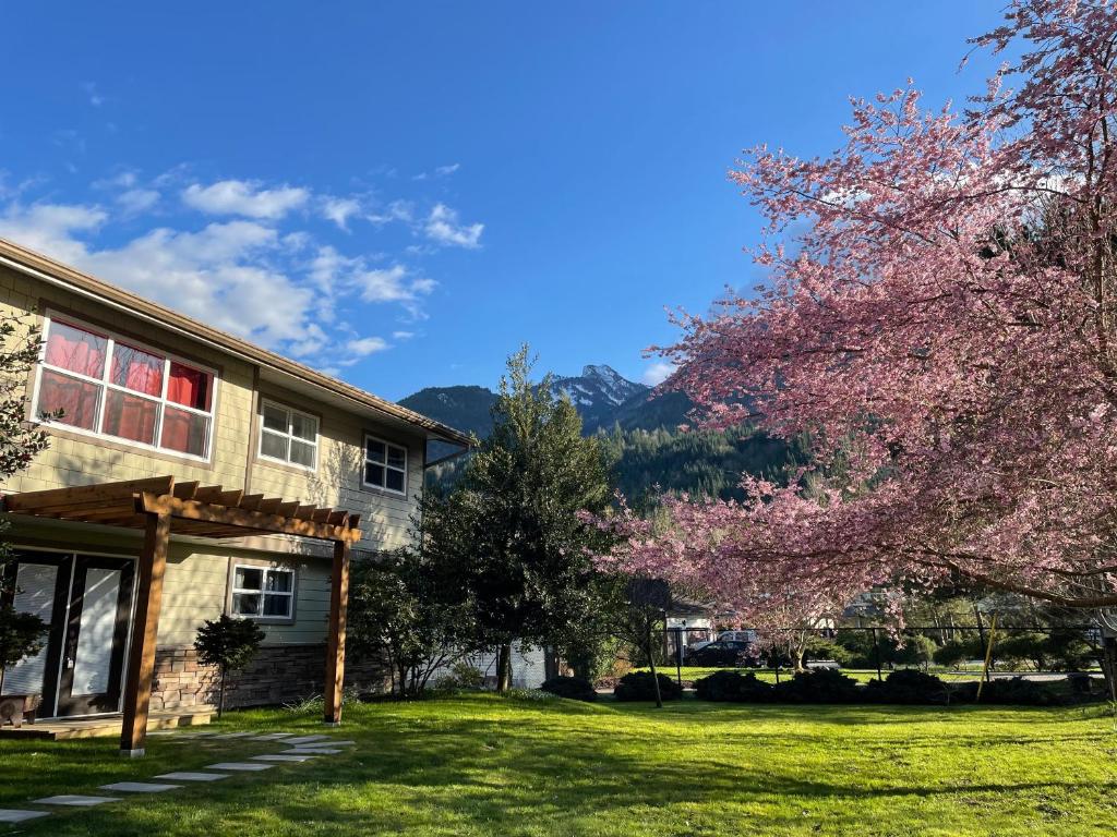 una casa y un árbol con flores rosas en el patio en Unique Upper Suite Near Lakes, River, Hiking, Fishing, Bike Trails en Chilliwack