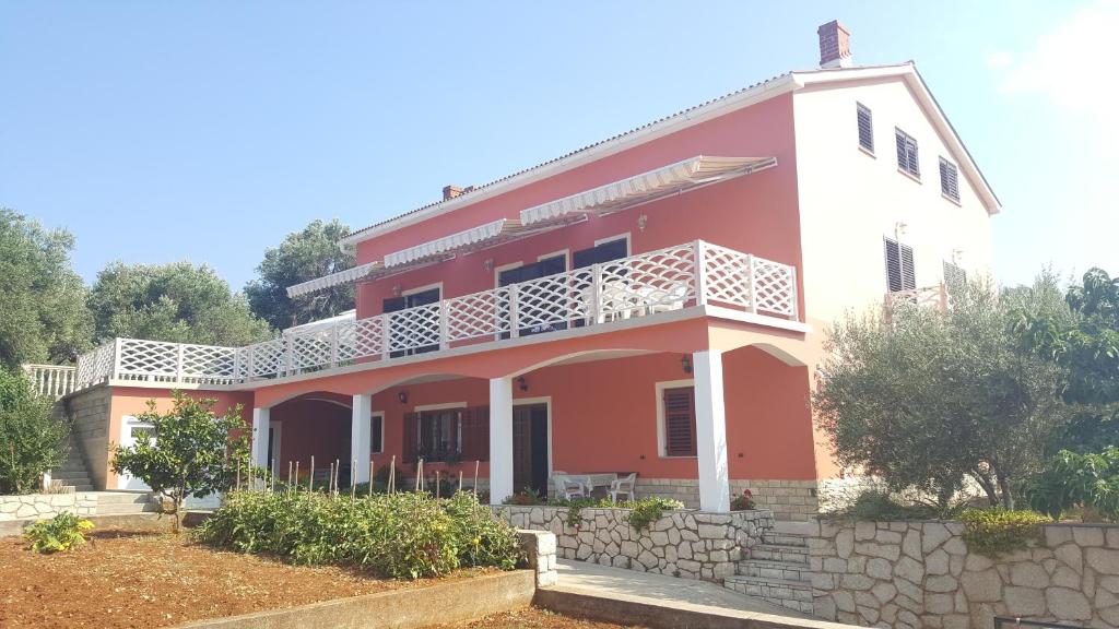 ein rotes und weißes Haus mit einer Steinmauer in der Unterkunft Apartments by the sea Lun, Pag - 11781 in Lun
