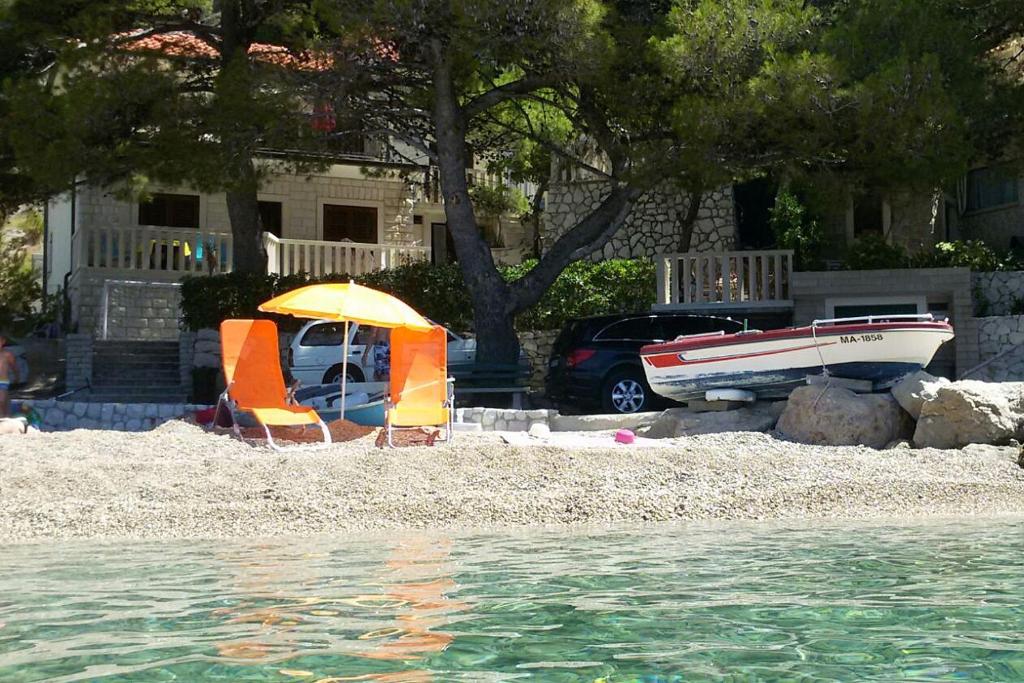 a beach with an umbrella and a boat on it at Apartments by the sea Brela, Makarska - 11821 in Brela