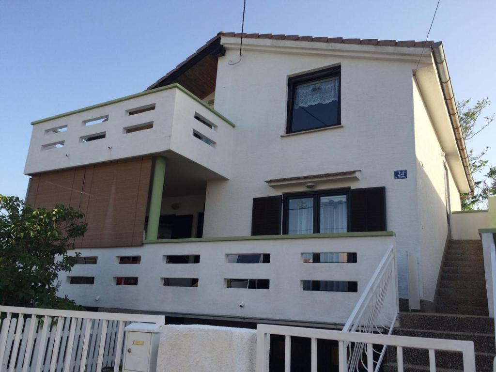 een wit huis met een wit hek ervoor bij Apartments by the sea Ugljan - 11820 in Ugljan
