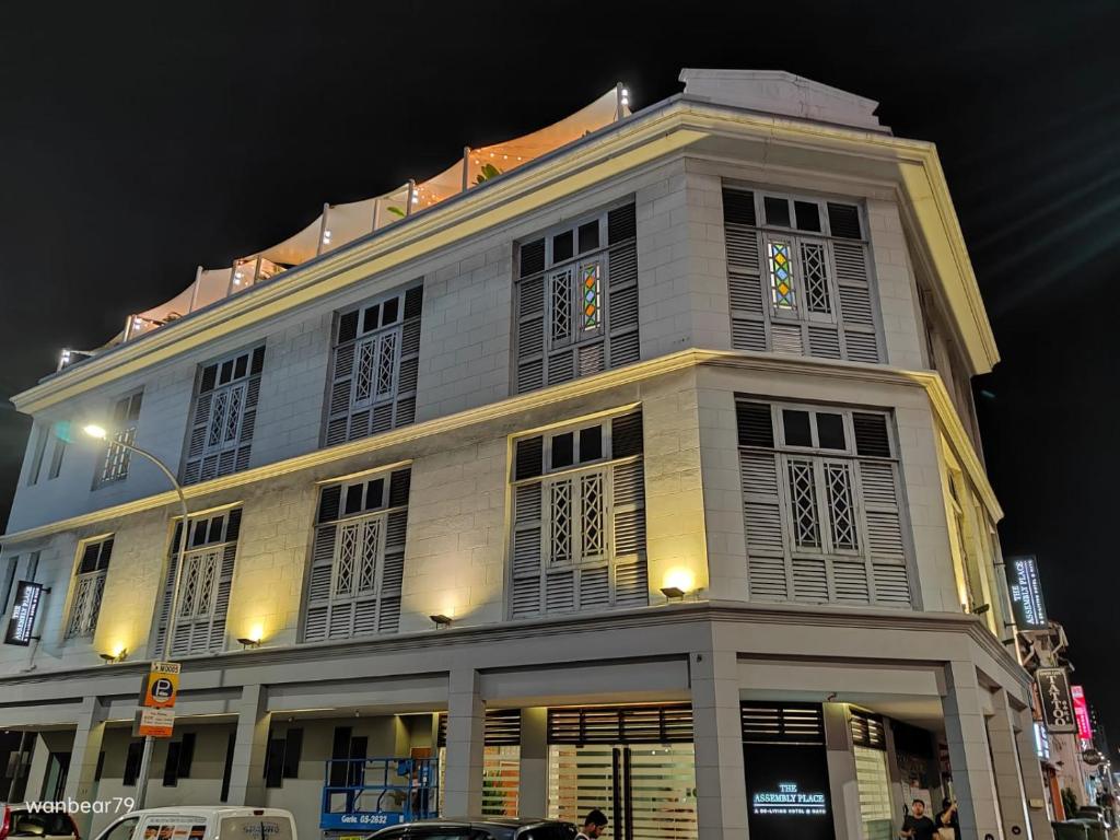 a large white building with shuttered windows at night at The Assembly Place, A Co-living at Mayo in Singapore
