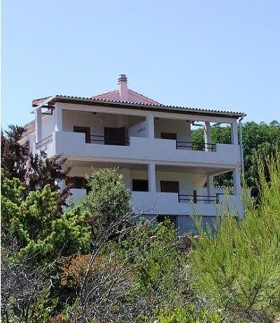 a white building on top of a hill with trees at Apartments with a parking space Rukavac, Vis - 11855 in Vis