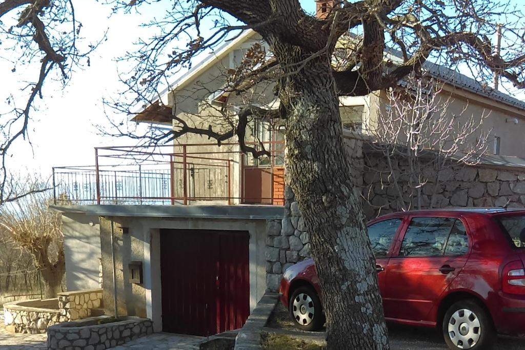 a red car parked in front of a house at Apartments with a parking space Smrika, Kraljevica - 12055 in Šmrika