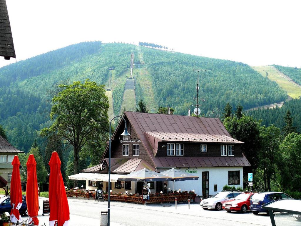 a restaurant with red umbrellas in front of a mountain at Pension Faema in Harrachov