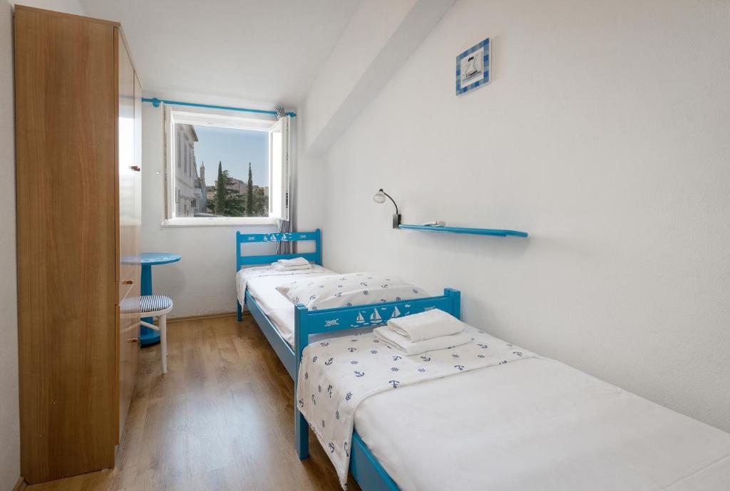 two beds in a small room with a window at Apartments by the sea Baska Voda, Makarska - 12209 in Baška Voda