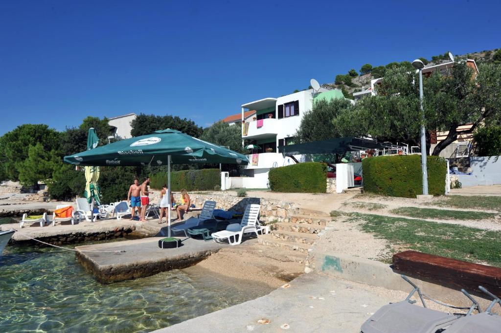 ein Pool mit Stühlen und einem Regenschirm und Menschen im Wasser in der Unterkunft Seaside house for families with children Zatoglav, Rogoznica - 12212 in Rogoznica