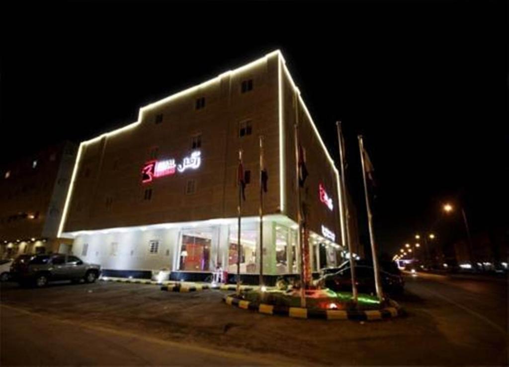 a building with a sign on the side of it at night at Refal Housing in Riyadh