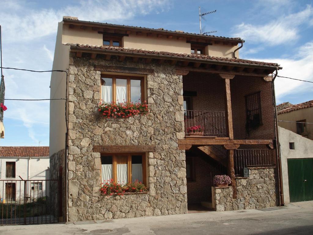 un edificio de piedra con cajas de flores. en Casa Rural Los Barreros, en San Cristóbal de Segovia