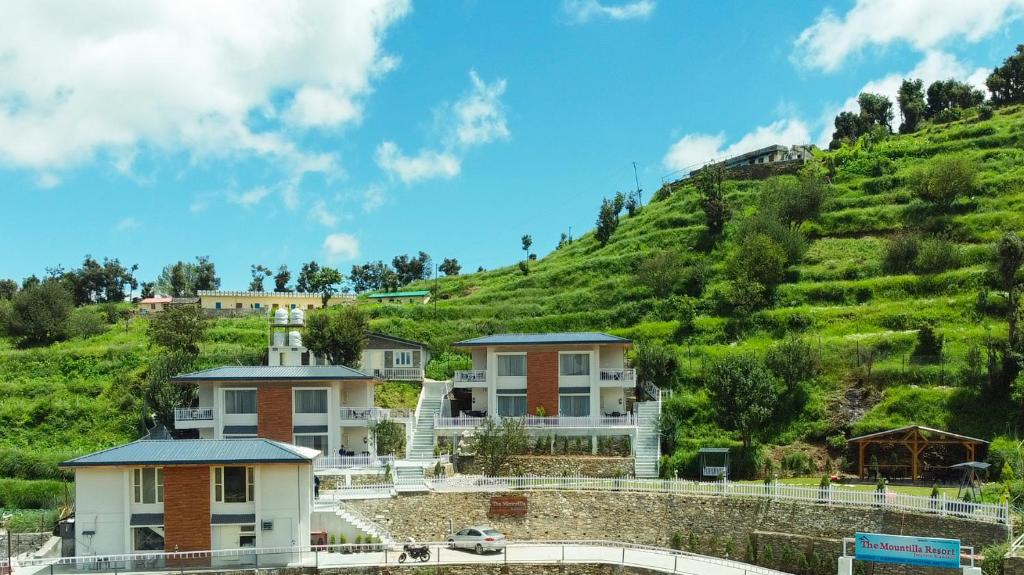 una casa en una colina con una colina verde en The Mountilla Resort, en Tehri-Garhwāl
