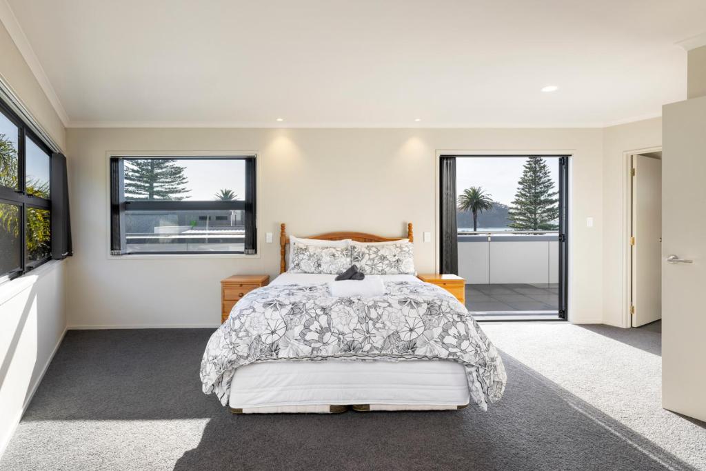 1 dormitorio con 1 cama y ventanas grandes en Pacific Escape - Downtown, Beach & Sea Views, en Mount Maunganui