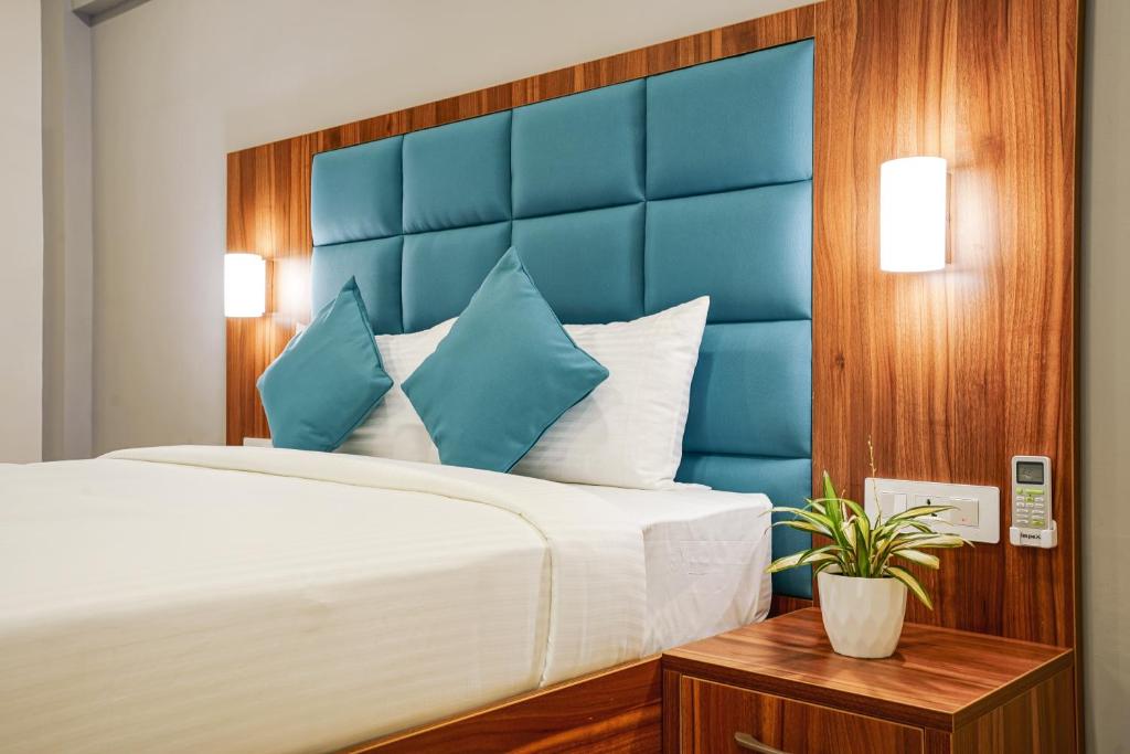 a bedroom with a large bed with a blue headboard at Inn Temple Town in Guruvāyūr