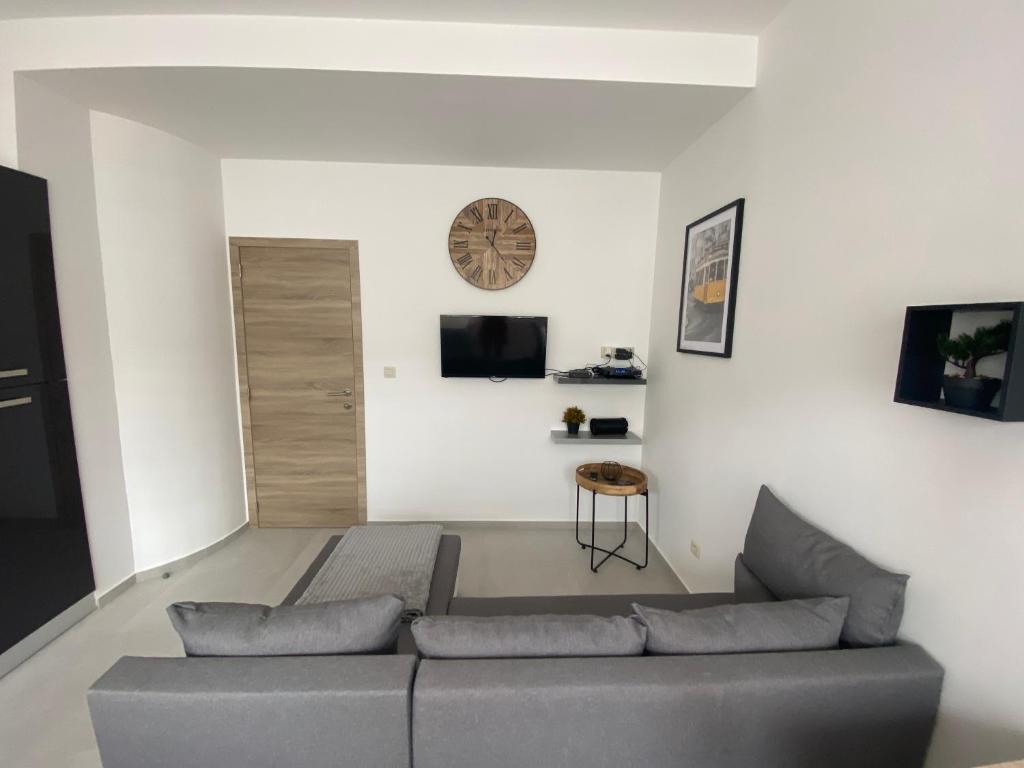 a living room with a couch and a clock on the wall at 010-Superbe appartement bien décoré netflix gratuit in Charleroi