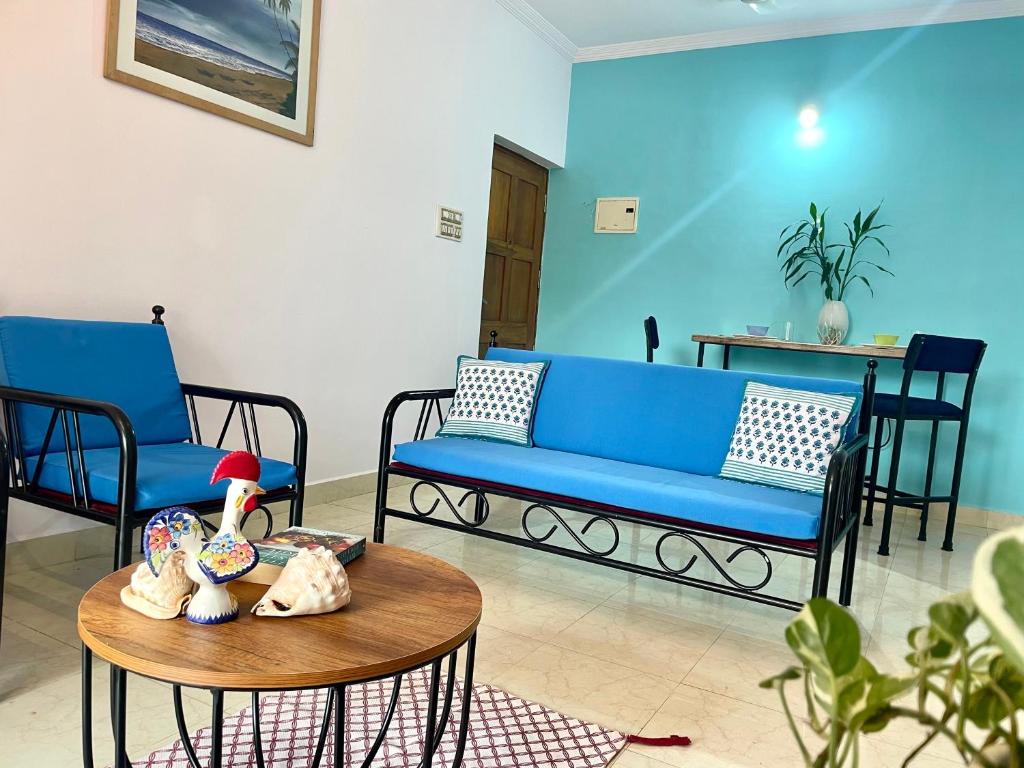 a living room with a blue couch and a table at Sun-kissed Holidays, Goa Topaz in Candolim
