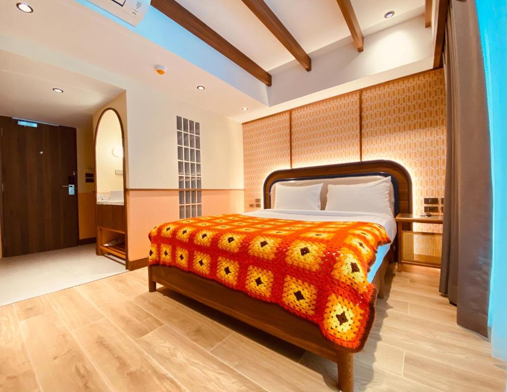 a bedroom with a bed with an orange blanket at Miami Hotel Bangkok - SHA Plus in Bangkok