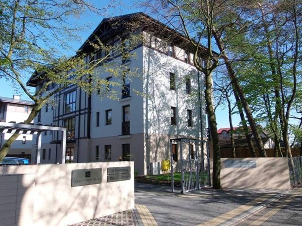 duży biały budynek z drzewem przed nim w obiekcie Apartament "Rezydencja Park" w Mielnie w mieście Mielno