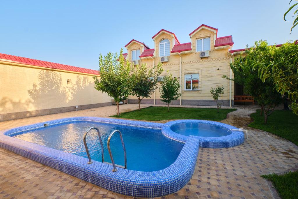 a swimming pool in front of a house at Gunesh Hotel Samarkand in Khodzha-Akhrar