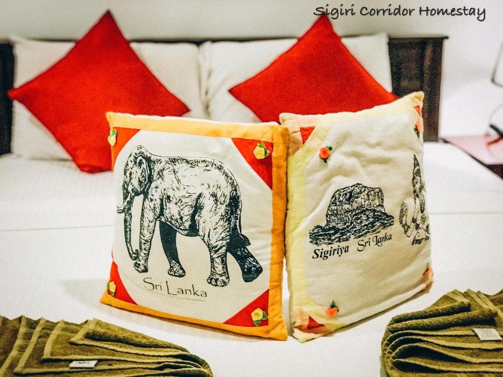 twee kussens op een bed met rode kussens bij Sigiri Corridor Home Stay in Sigiriya
