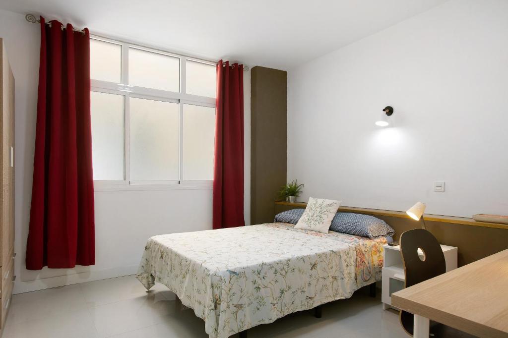 ein Schlafzimmer mit einem Bett und einem Fenster mit roten Vorhängen in der Unterkunft Estudio Massimo 7d in Las Palmas de Gran Canaria