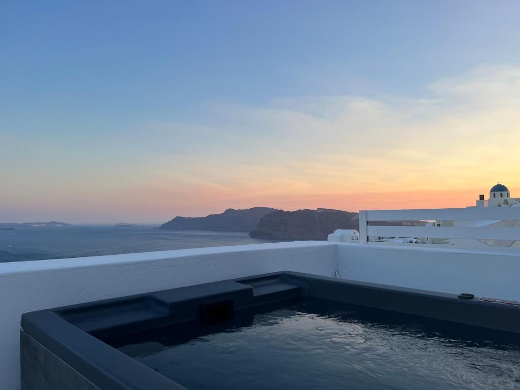 a swimming pool on the side of a building with the sunset at Imerti Suites in Oia