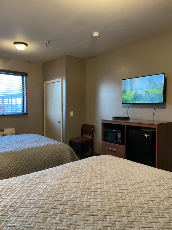 a hotel room with two beds and a flat screen tv at Plaza Inn in Sabetha