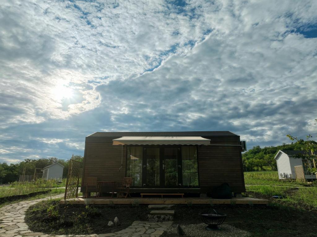 uma pequena casa num campo sob um céu nublado em 1001 Village em Jugureni