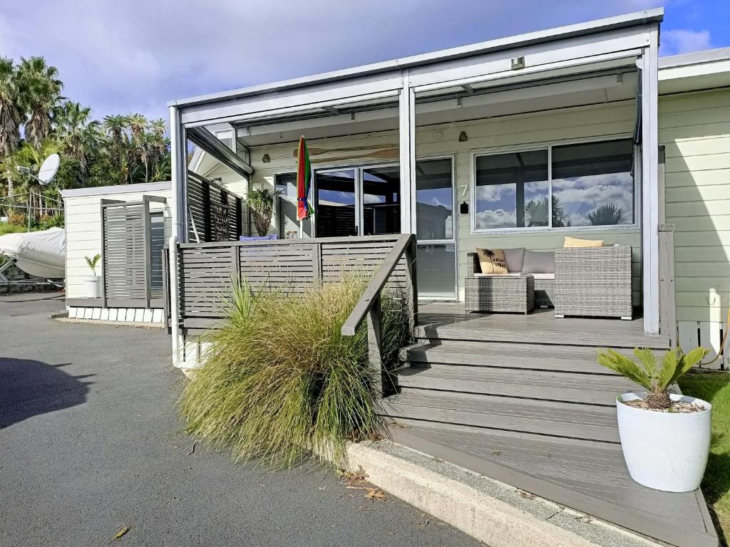 a house with a wooden porch with glass doors at Adorable Beach Unit Stanmore Bay in Whangaparaoa
