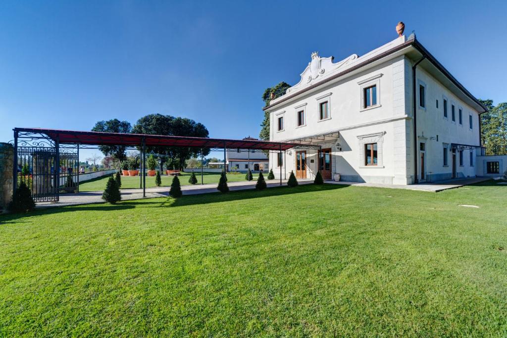 a large grassy field next to a white building at Villa Tolomei Hotel & Resort in Florence