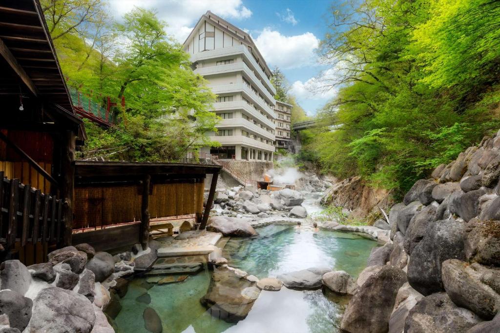 Nikko Nationalpark Kawamata Onsen KURA في نيكو: نهر فيه صخور امام مبنى