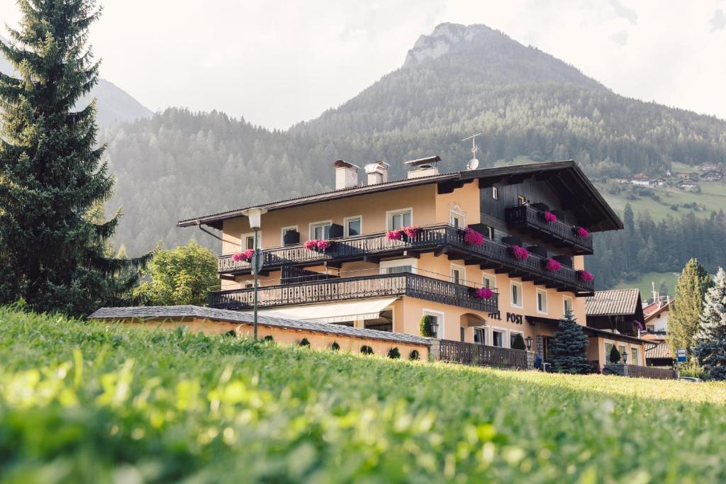 a building on a hill with a mountain in the background at Posthotel in Lutago