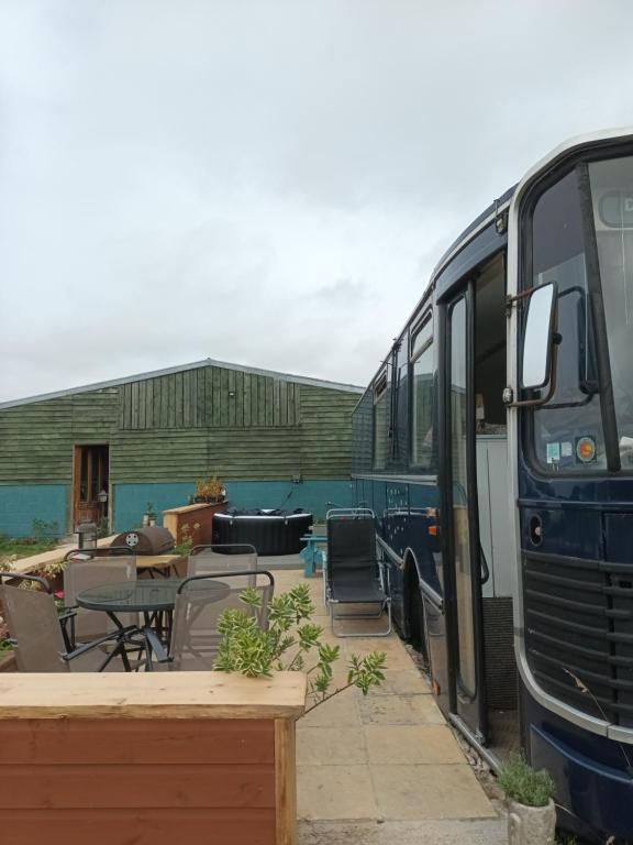 niebieski autobus zaparkowany obok stołu i krzeseł w obiekcie Converted French bus with stunning views w mieście Exeter