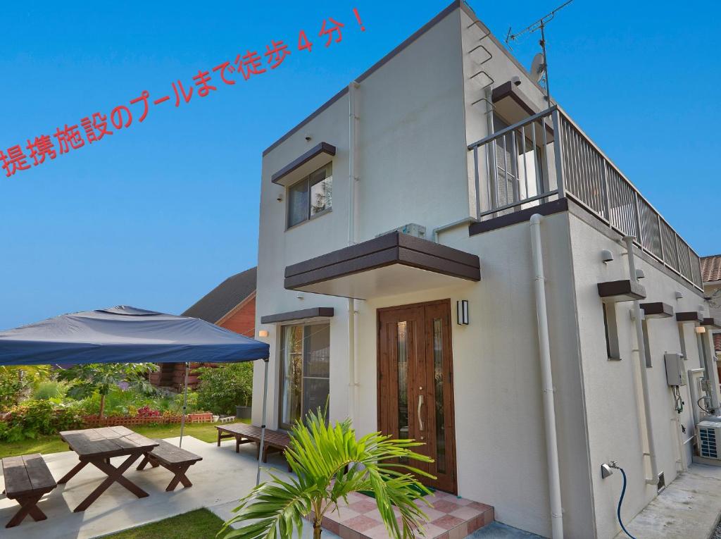 a house with a balcony and a table and an umbrella at The Pool Resort Villa Hasta Manana in Onna