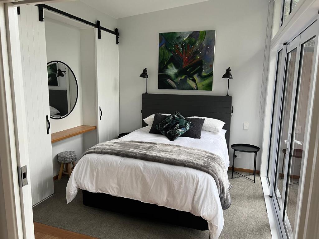 a bedroom with a large bed and a mirror at Torbay Tree Tops in Auckland