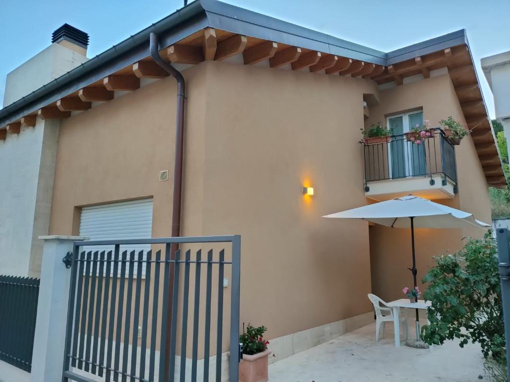 uma casa com uma varanda com um guarda-chuva e uma mesa em Villino Maria Pia, appartamento in villino in centro storico L'Aquila em LʼAquila