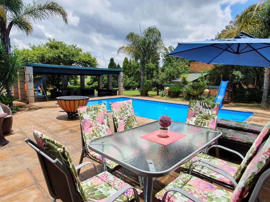 a table with chairs and an umbrella next to a pool at Sunrise Serenity Guest House in Lydenburg