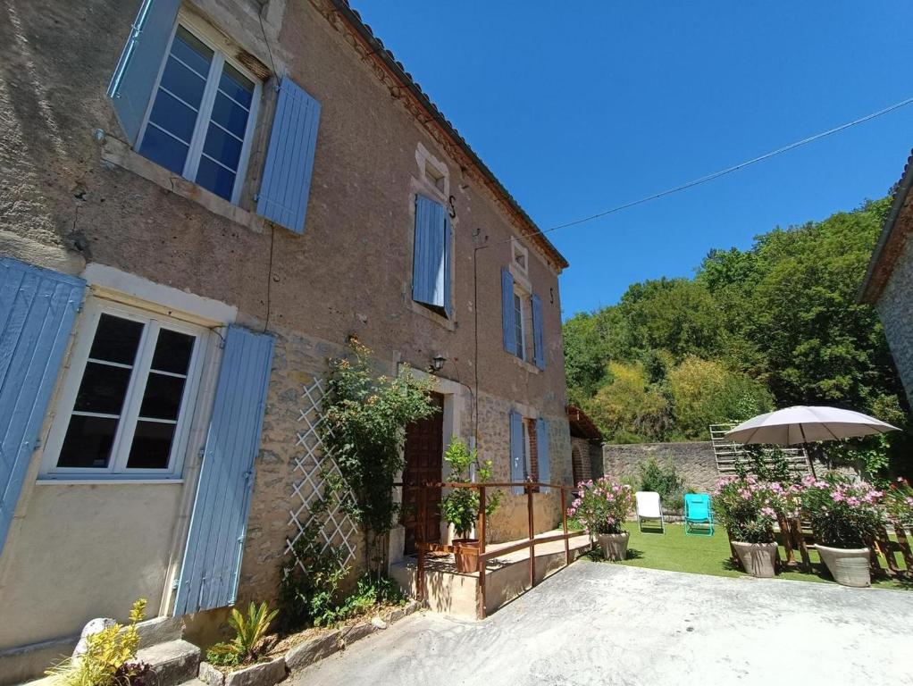 uma casa de tijolos com um guarda-chuva em frente em Maison sur le Lot em Saint-Vincent-Rive-dʼOlt