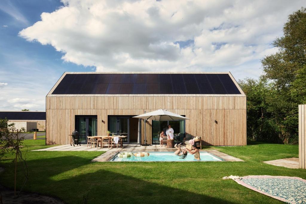 een huis met een zonnedak en een zwembad bij Resort Brinckerduyn in Appelscha