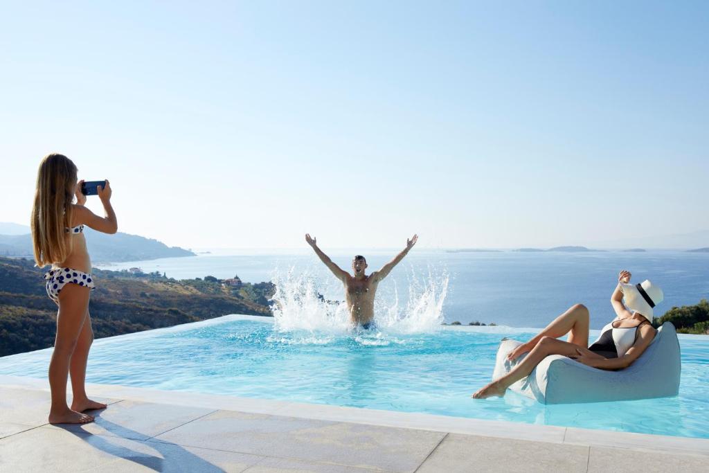 una mujer tomando una foto de un hombre en una piscina en Eagles Palace, en Ouranoupoli