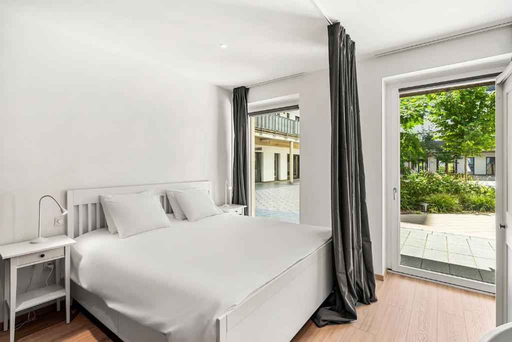 a white bedroom with a large bed and a window at VibeStudio 403 - Central - AC - Licensed - Parking Nearby in Vienna