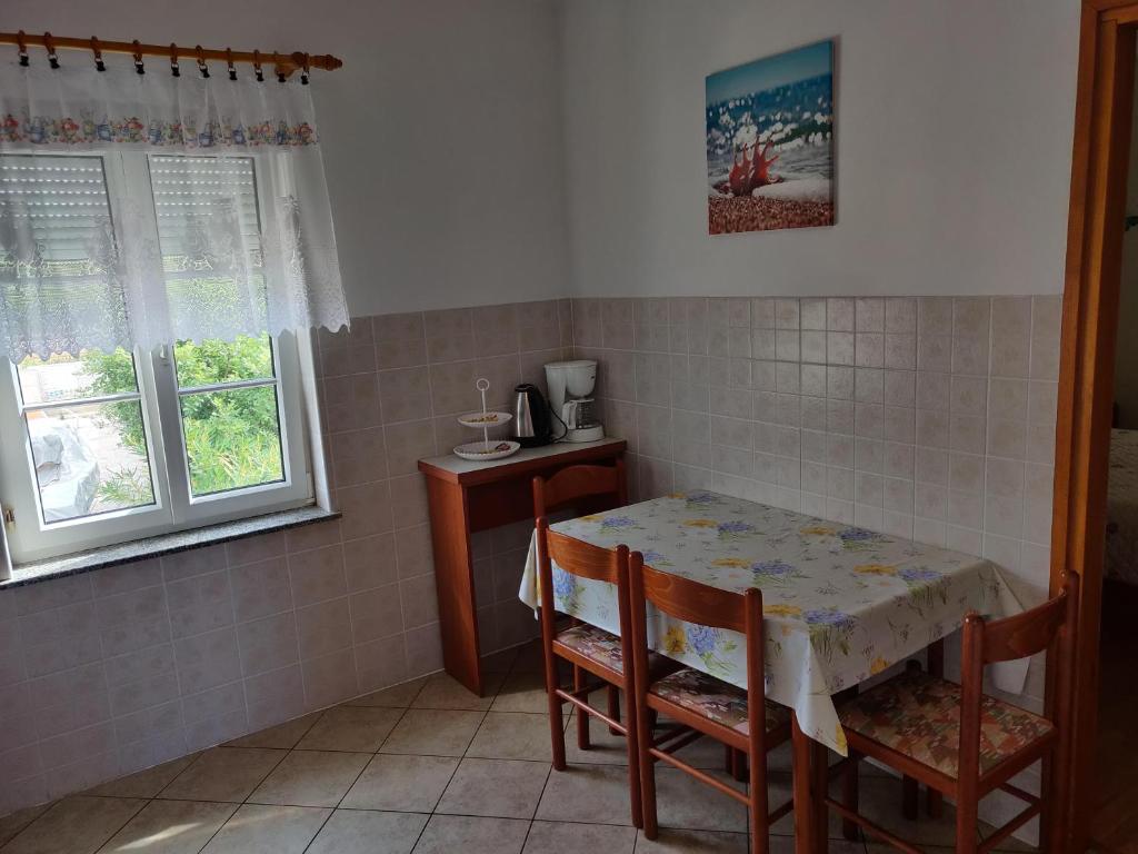 a kitchen with a table and chairs and two windows at Apartment Nenadic in Hrahorić