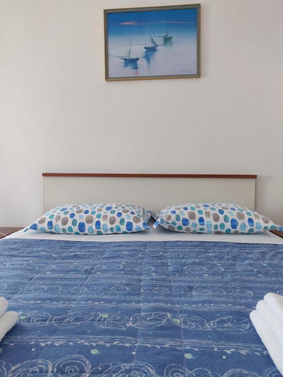 a bed with a blue comforter and two pillows at Apartment Nenadic in Hrahorić