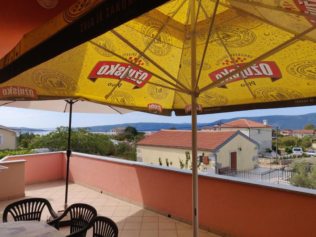 a yellow umbrella on a balcony with a table and chairs at Apartment Nenadic in Hrahorić