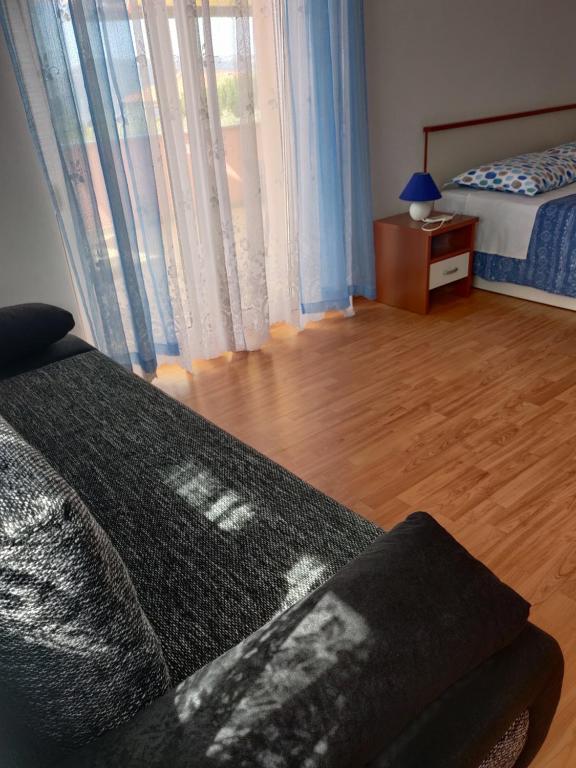 a bedroom with a bed and a wooden floor with a window at Apartment Nenadic in Hrahorić