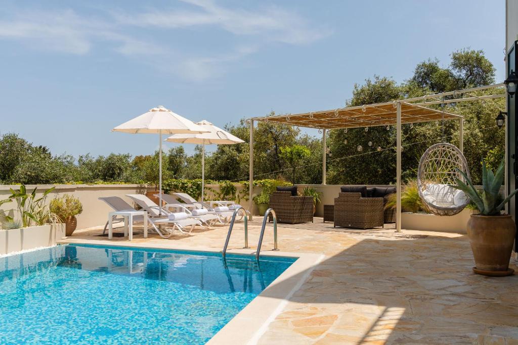 a swimming pool with chairs and an umbrella at Villa Leveque - Kassiopi Hillside pool villa in Kassiopi