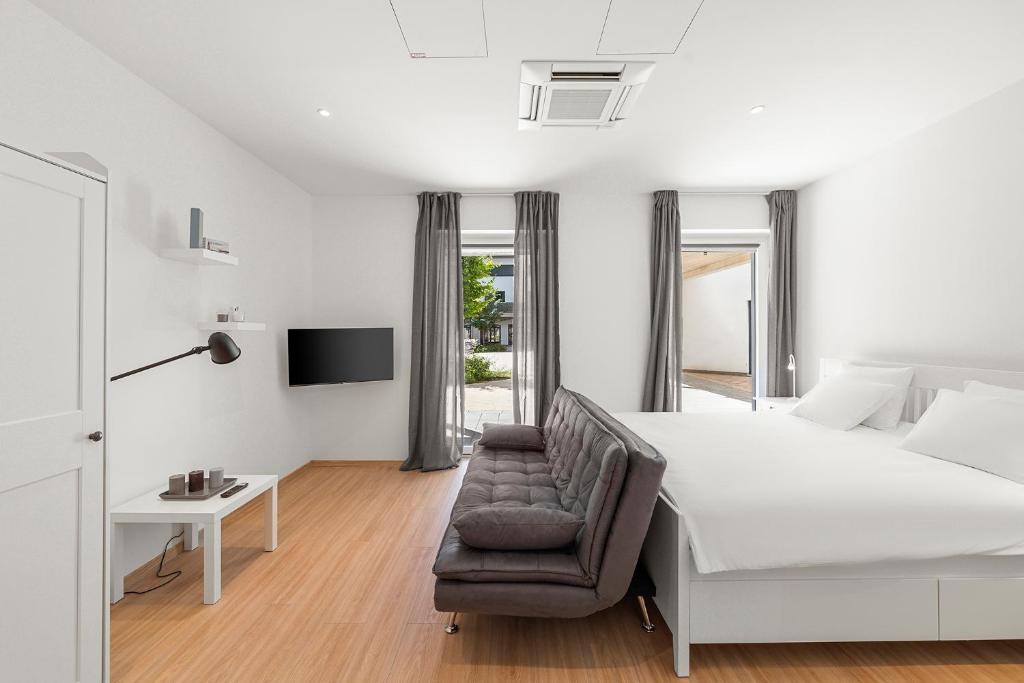 a white bedroom with a bed and a chair at VibeStudio B2 - Central Vienna 1090 - 50m2 - Self Check-In - AC in Vienna