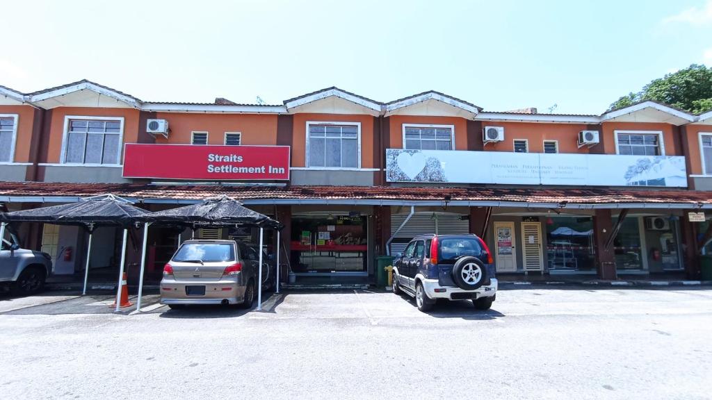 dos autos estacionados en un estacionamiento frente a un edificio en Straits Settlement Inn en Melaka